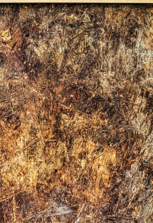 Close photograph of Whisper: a scratched, ridged surface in brown, amber and gold below its light wood frame