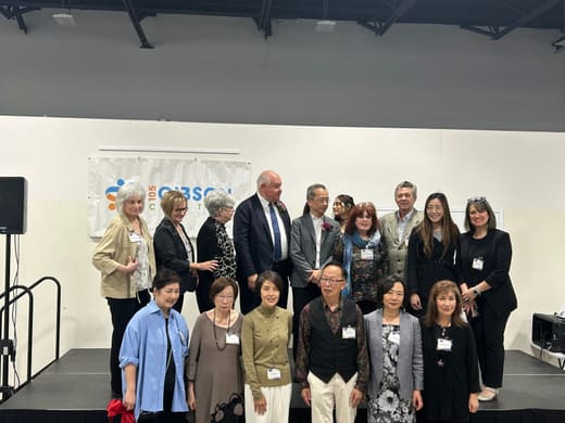 Group photograph on the stage after the ribbon-cutting, in front of the 105 Gibson Centre banner