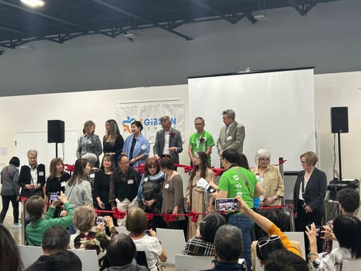 A row of people on the stage holding a red ribbon at the opening ceremony